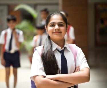 Portrait of confident girl with arms crossed in school uniform